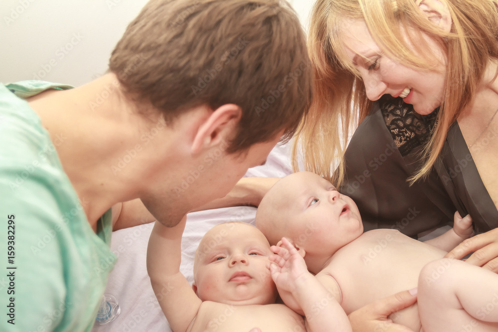 indoor portrait of young happy smiling mother and father with twin babies at home indoor portrait of young happy smiling mother and father with twin babies at home