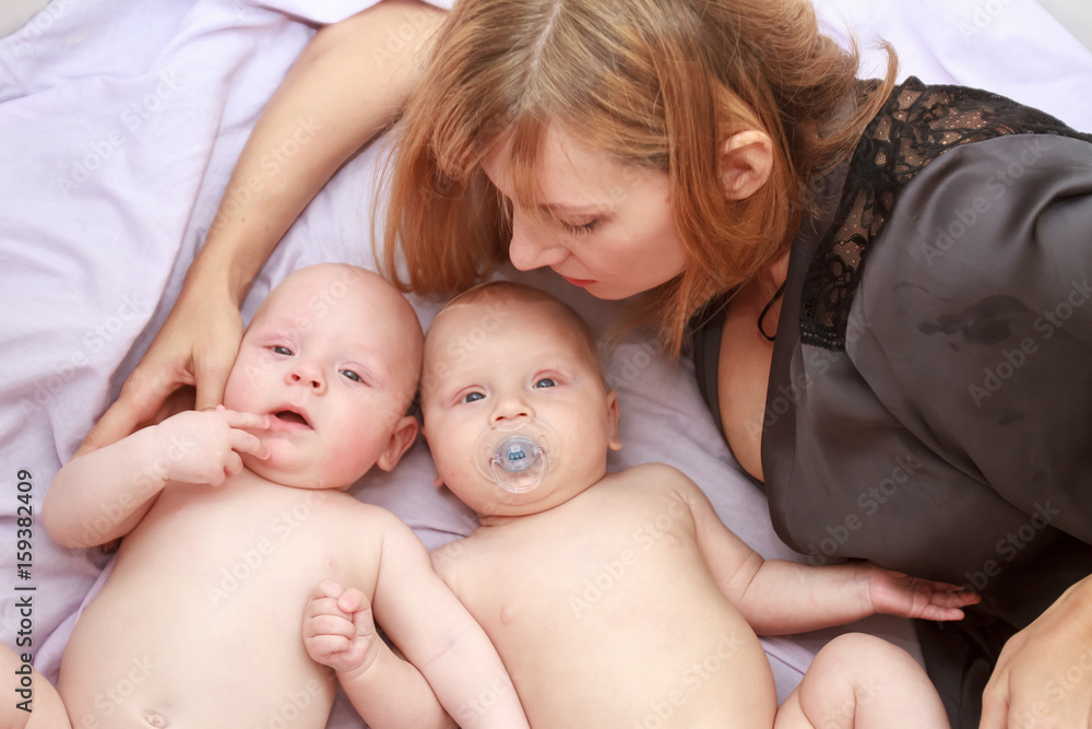 indoor portrait of young happy smiling mother with her twin babies at home indoor portrait of young happy smiling mother with her twin babies at home