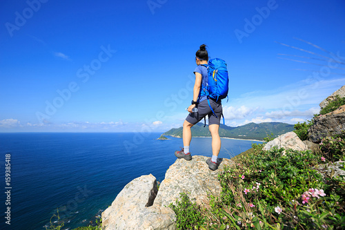 successful woman backpacker enjoy the view on seaside mountain rock