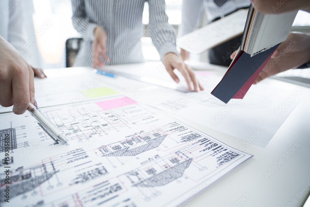 They are meeting at the office looking at the design drawing They are meeting at the office looking at the design drawing