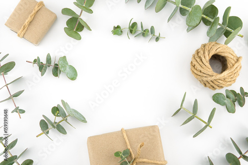 Brown gift boxes and ropes decorated with baby eucalyptus leaves with copy space in the center on white background
