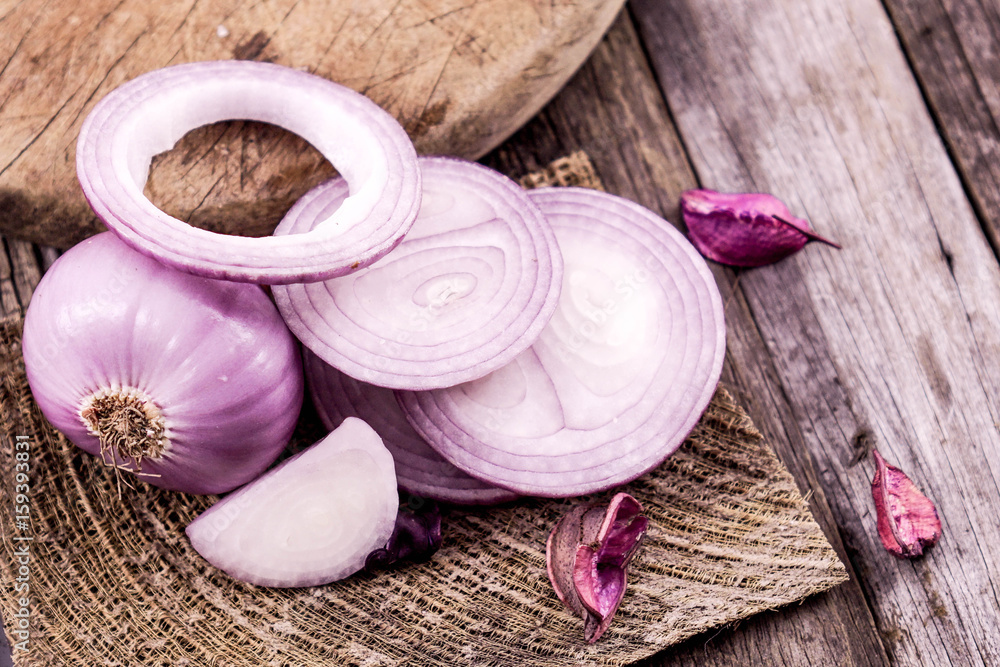 close up of sliced red onion and whole red onion on a wooden table close up of sliced red onion and whole red onion on a wooden table