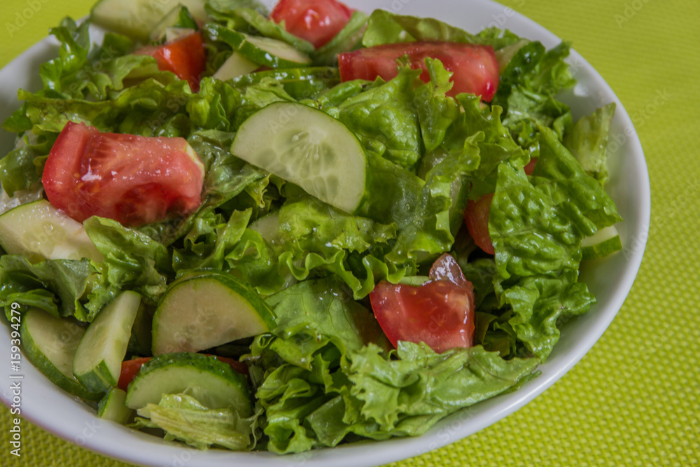 Fresh salad. Tomato, cucumber and greens in white bowl Fresh salad. Tomato, cucumber and greens in white bowl