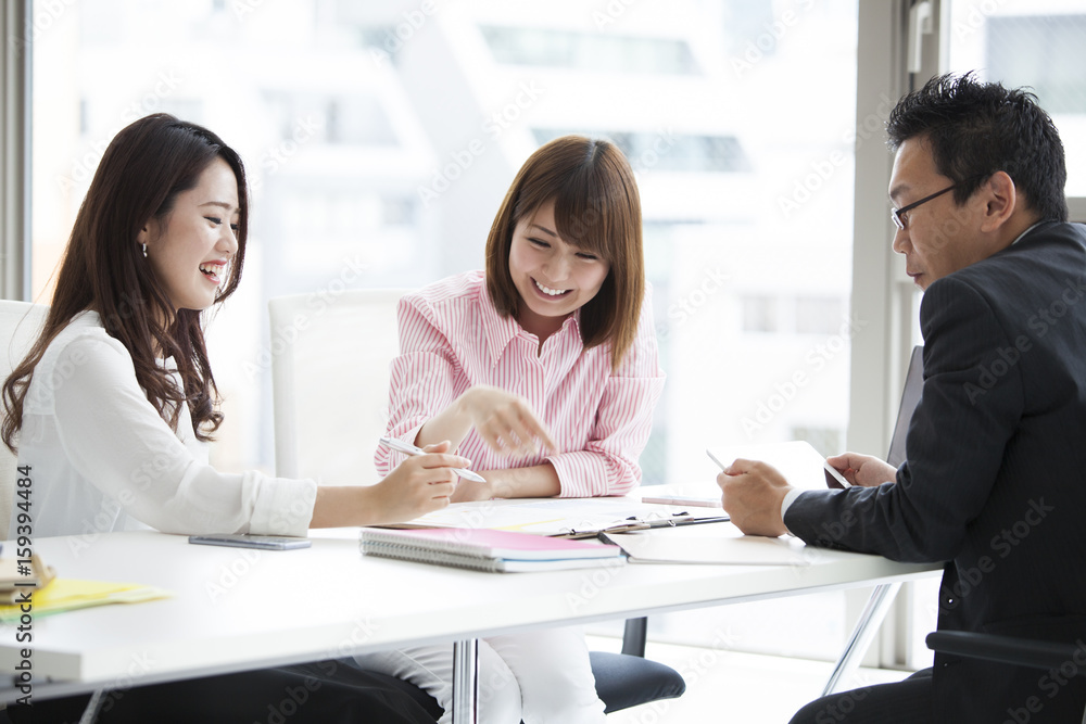 Three office workers are meeting at a bright office Three office workers are meeting at a bright office