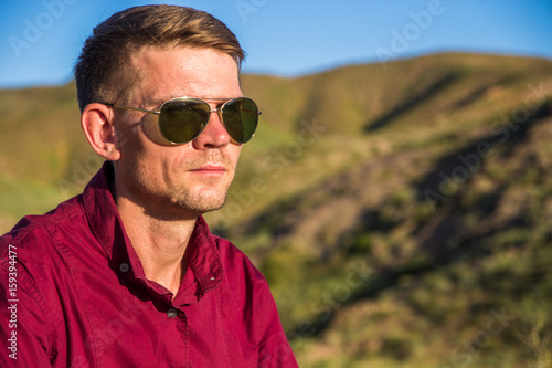 Young man in red shirt at steppe in sunny day, Kazakhstan
