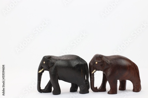 Close up of hand carved wooden elephants standing side by side isolated on white background 