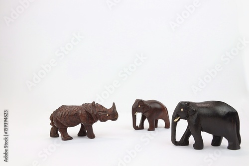 Two hand carved wooden elephants facing wooden rhinoceros 