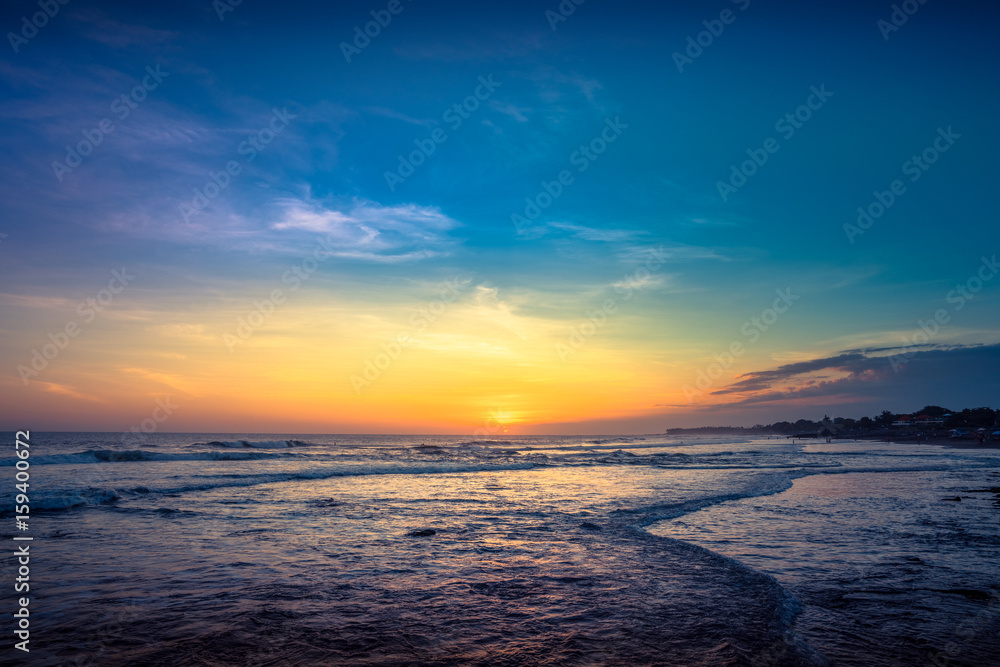 Sunset Background Ocean. Tropical Sunlight and Summer Sunset View. Colorful Background Sunset. Blue Waves near sea Resort. Sea sunset Background. Colorful Beach with Surfers on the Horizon. Landscape