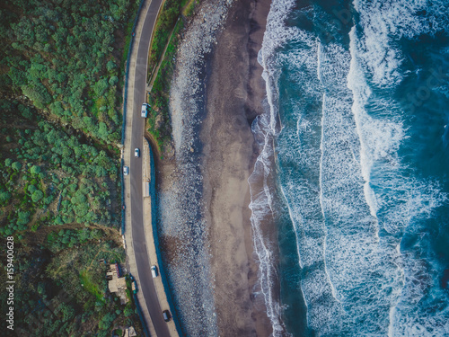Volcanic sunset beach in Tenerife, Benijo. Paradise beach in Canary Island. Flight above ocean waves, washing up on a black volcanic sand beach. Aerial shot of tide, sea, wide dramatic landscape view