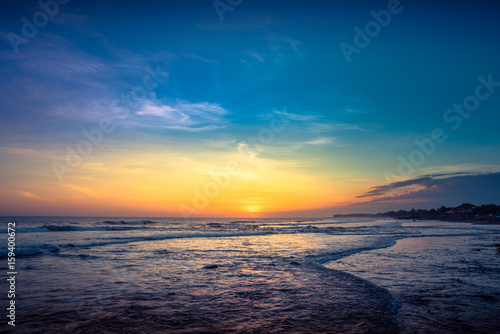 Sunset Background Ocean. Tropical Sunlight and Summer Sunset View. Colorful Background Sunset. Blue Waves near sea Resort. Sea sunset Background. Colorful Beach with Surfers on the Horizon. Landscape