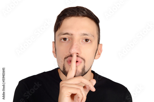 Young man with finger on lips making silence.