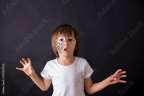 Sweet preschool child, painted as tiger, playing in studio