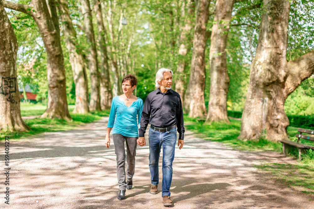 Senior Couple Walking Through A Park Senior Couple Walking Through A Park
