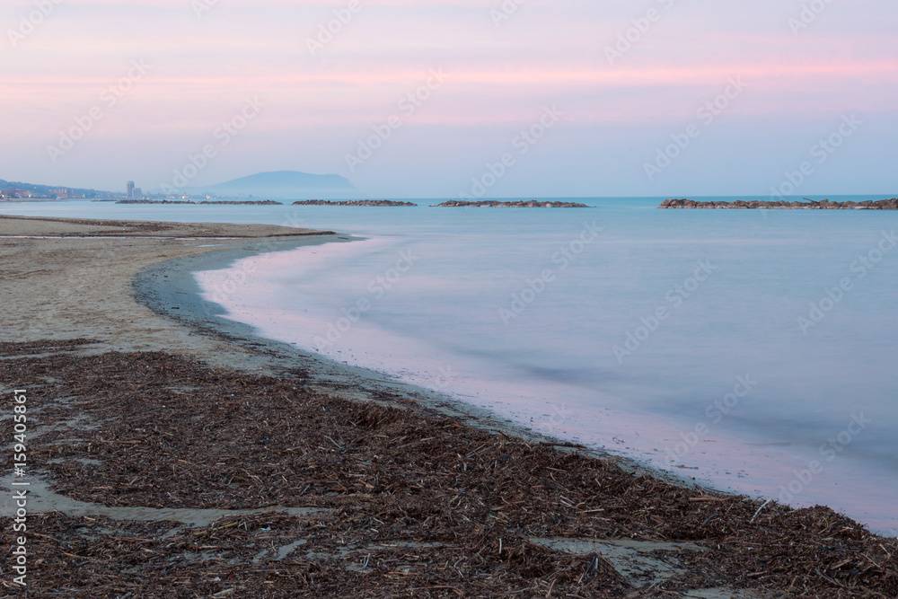 A sea shore at dusk, with beautiful warm and soft colors in the sky
