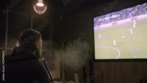 Wallpaper Mural Man watching football on the big screen and smoking hookah Torontodigital.ca