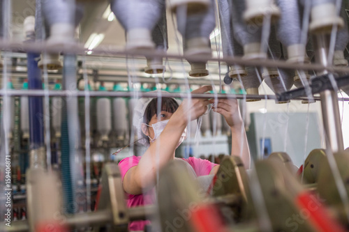 female worker standing beside thread making machine inside cotton mill,industry concepts. photo