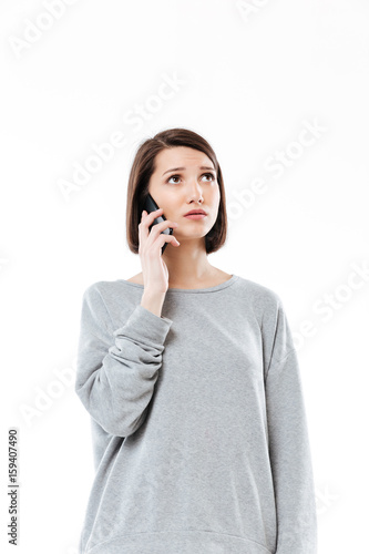Sad young caucasian woman talking by phone.