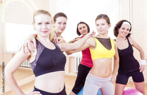 Healthy Lifestyle Concepts. Closeup Portrait of Five Happy Caucasian Female Athletes Posing Together Embraced Against Fitballs in Gym.