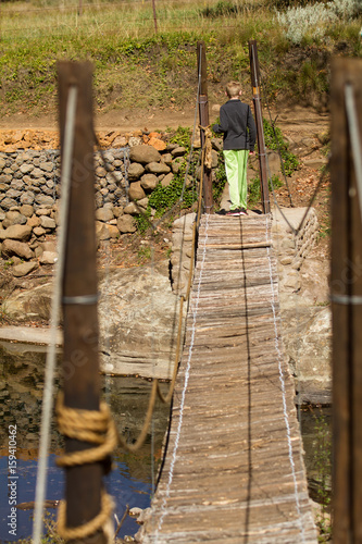 boy crossing bridge over stream photo