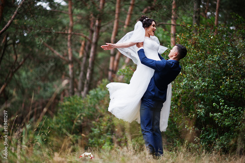 Beautiful young wedding couple admiring each other in a pine tree forest.