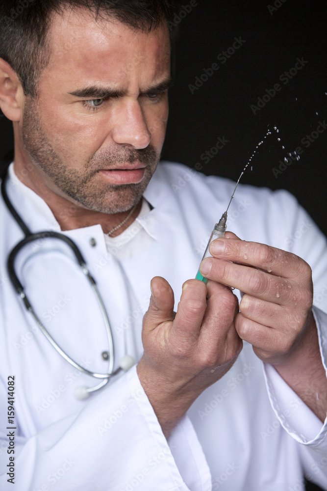 doctor holding a syringe and looking at it doctor holding a syringe and looking at it