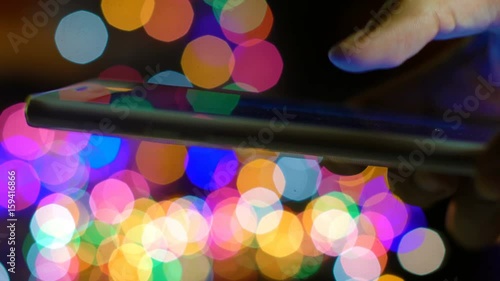 Using smartphone and christmas blurred lights on background. Shallow DOF 4k UHD (3840x2160)
