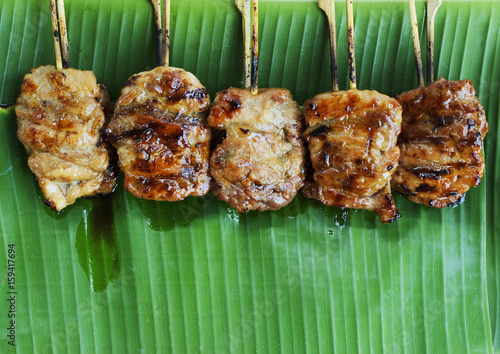 Grilled pork or mooping thai local street food on banana green leaf backgrounds above photo