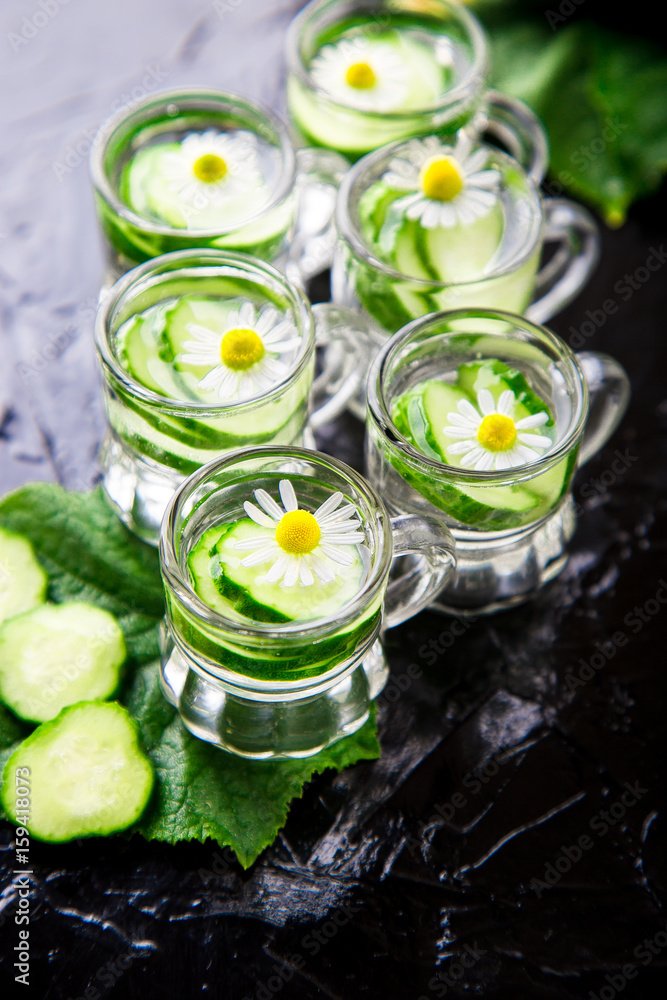 Cucumber water in six little mason glass jar on black background. Cucumber water in six little mason glass jar on black background.