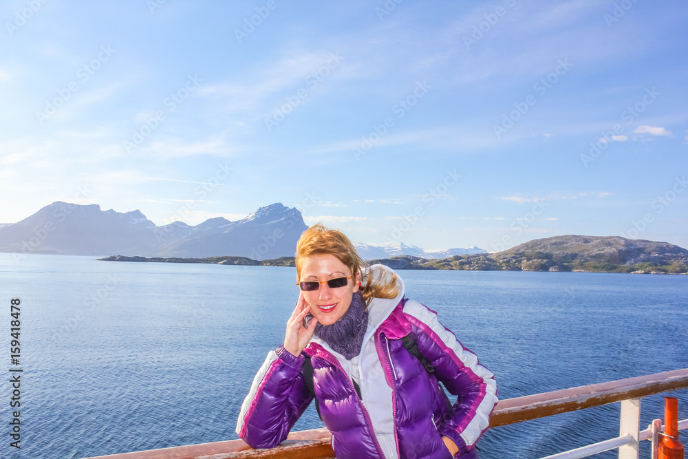 Norway cruise ship happy tourist enjoying trip to Northern Europe. Cruise on Norwegian Fjords. Caucasian woman on travel vacation ship. Spectacular landscapes of Lofoten Islands. Summer holidays.