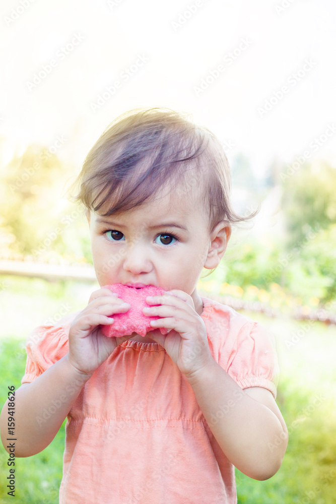cute little girl eating watermelon on the grass in summertime cute little girl eating watermelon on the grass in summertime