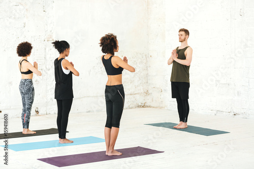 Group of multicultural women practicing yoga with male instructor