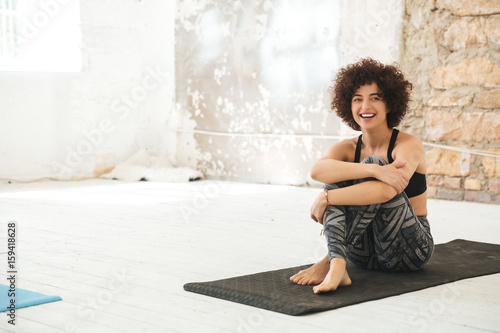 Happy young woman sitting in yoga studio