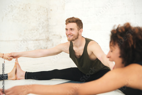 Happy multiethnic people in yoga studio stretching.