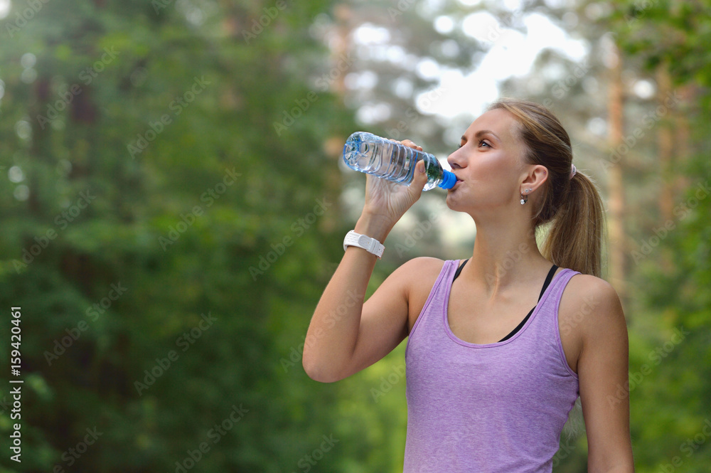 Young woman drinking water after jogging Young woman drinking water after jogging