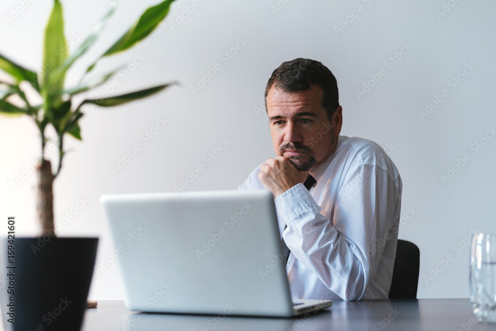 Senior man in office working on laptop computer Senior man in office working on laptop computer