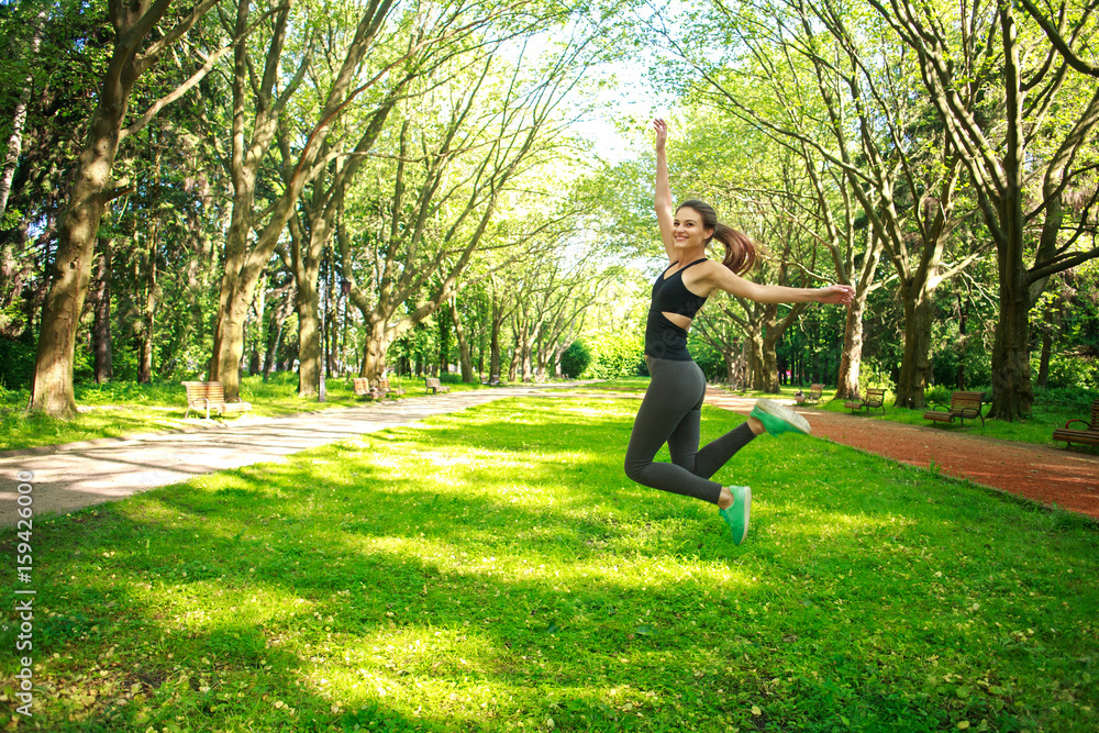 Sportive young fitness woman jumping in summer park Sportive young fitness woman jumping in summer park