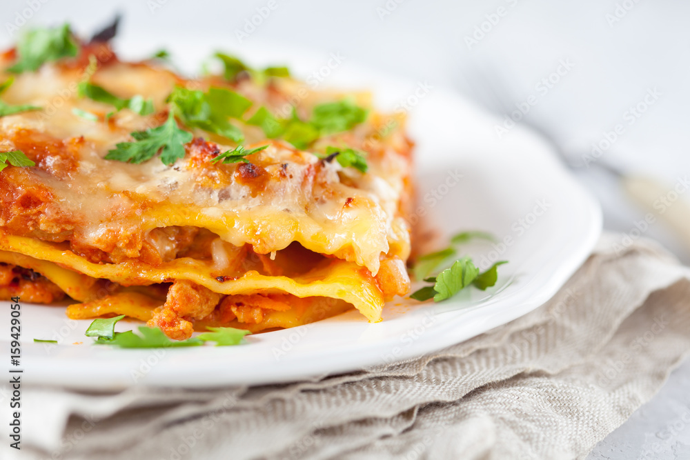 Piece of traditional Italian meat lasagna on a white plate.