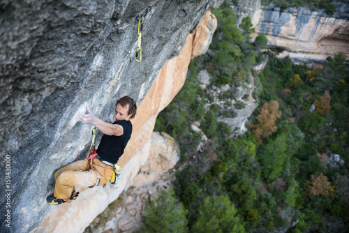 Outdoor sport activity. Rock climber ascending a challenging cliff. Extreme sport climbing.