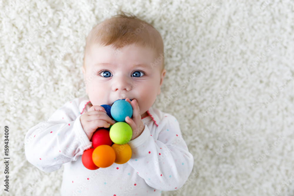 Cute baby girl playing with colorful wooden rattle toy Cute baby girl playing with colorful wooden rattle toy