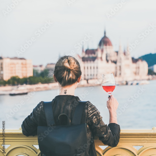 Photography Young woman tourist standing with glass of rose wine at Margaret bridge in Budap