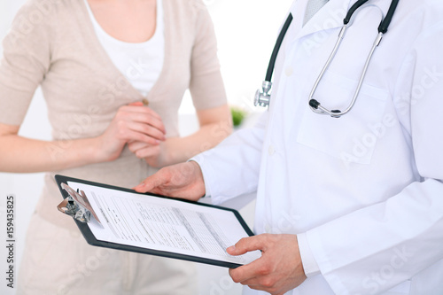 Close up of a male doctor holding an application form while consulting patient