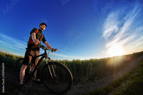 Fototapeta Naklejka Na Ścianę i Meble -  Portrait of the cyclist with mountain bike on a background of blue sky with clouds.