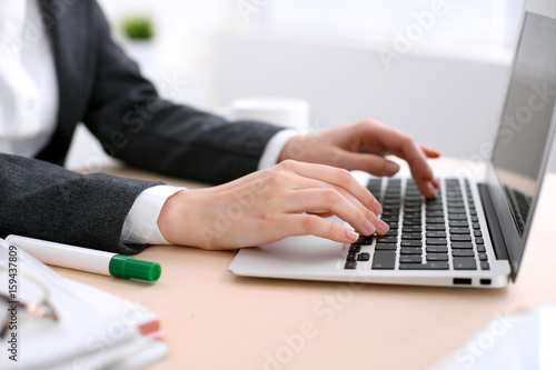Fototapeta Naklejka Na Ścianę i Meble -  Close up of business woman  hands  typing on  laptop computer in the white colored office.