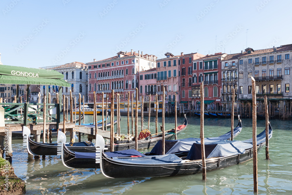 Fototapeta premium Row of gondolas moored on the Grand Canal , Venice , Italy in front of ancient palazzos in San Polo with the gondola station alongside in a tourism and travel concept