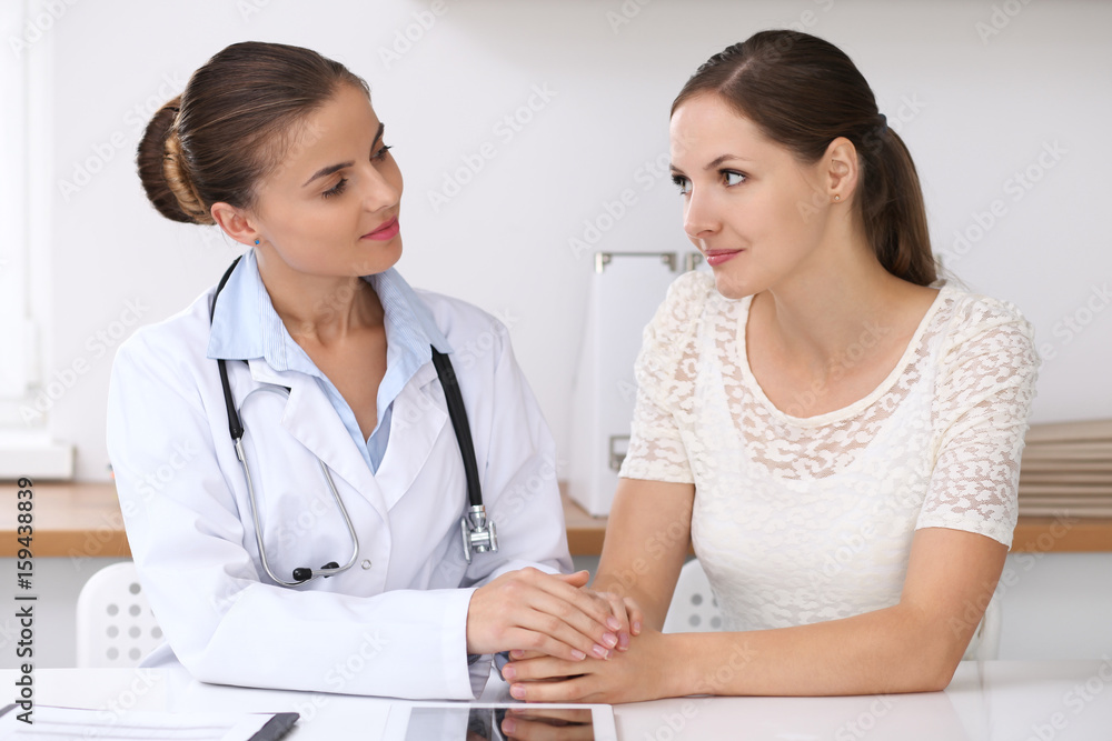 Doctor reassuring her female patient while sitting at the desk. Medicine, help and health care concept Doctor reassuring her female patient while sitting at the desk. Medicine, help and health care concept