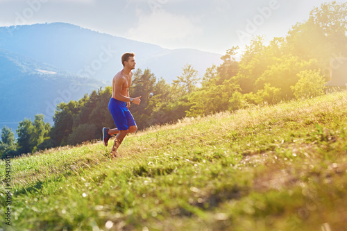Trial running concept - young athletic man exercising intervals running uphill