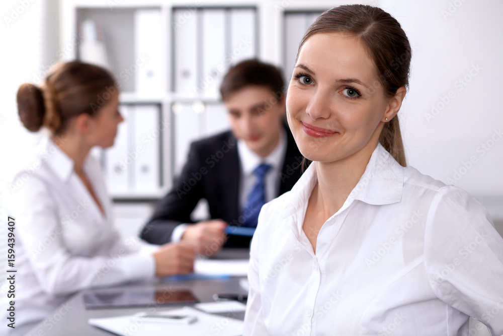 Group of business people at meeting on the background of office. Focus on a beautiful brunette Group of business people at meeting on the background of office. Focus on a beautiful brunette
