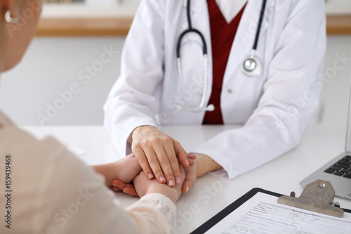 Hand of doctor  reassuring her female patient
