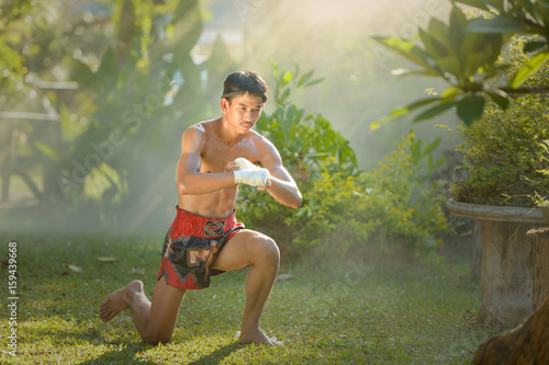 Fototapeta Naklejka Na Ścianę i Meble -  Muay thai, Thai Boxer training in sunset background,Thai boxer culture,Thailand