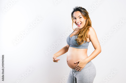 Beautiful pregnant latin woman pointing at her belly